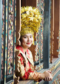 Portrait of smiling woman in traditional clothing peeking from window