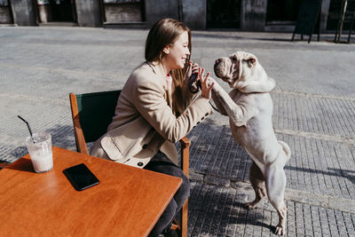 Rear view of woman with dog sitting on table