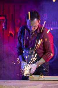 Man working on illuminated metal