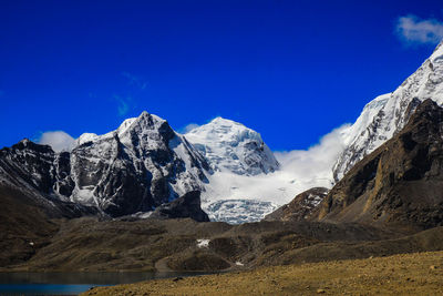 Scenic view of snowcapped mountains against blue sky