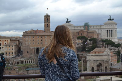 Rear view of woman at building terrace with city in background