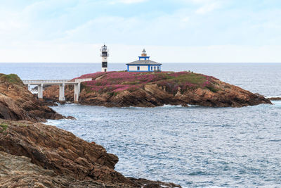 Lighthouse by sea against sky