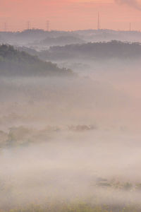 Scenic view of fog against sky during sunset