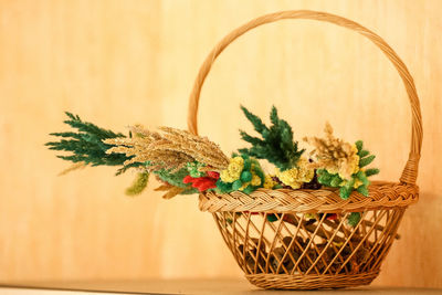 Close-up of potted plant in basket on table against wall