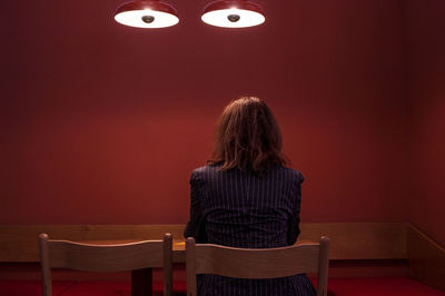 Rear view of woman standing against red wall