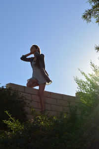 Low angle view of man standing against clear blue sky