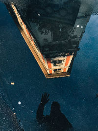 Low section of man standing by puddle in city