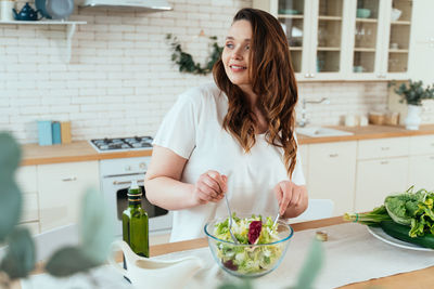 Midsection of woman eating food at home