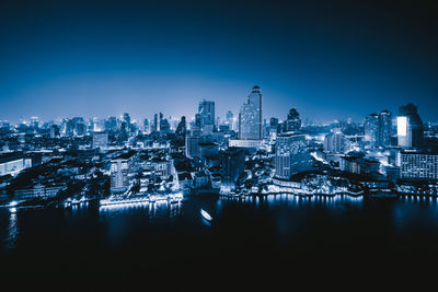 Illuminated buildings in city against clear sky at night