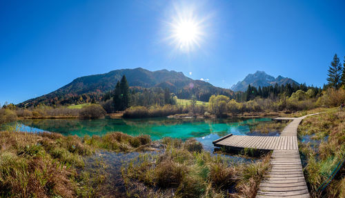 Scenic view of lake and mountains against clear blue sky