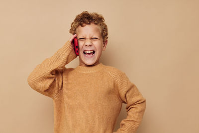 Boy talking on phone against beige backgrounds