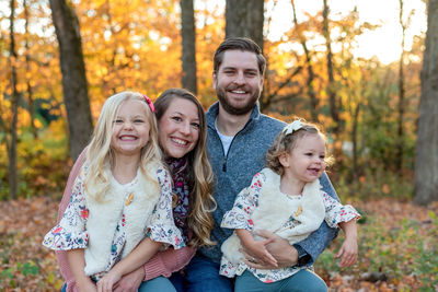 Portrait of happy family against trees during autumn