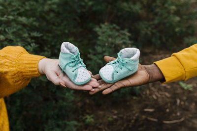 Close-up of couple holding baby booties at forest