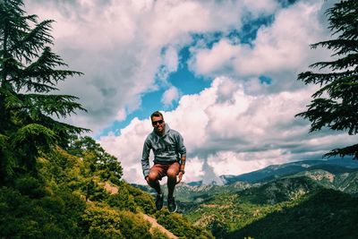 Full length of young man jumping against mountains