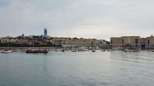 View of buildings by river against cloudy sky