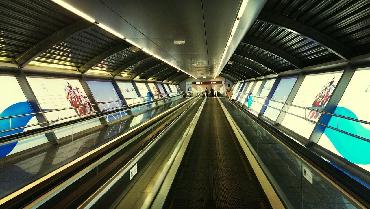 indoors, ceiling, architecture, built structure, diminishing perspective, the way forward, transportation, vanishing point, low angle view, rail transportation, interior, subway, empty, railroad station, illuminated, public transportation, no people, railing, modern, railroad track