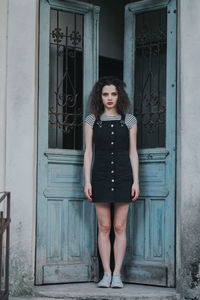 Portrait of beautiful young woman standing against closed door of building