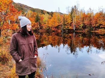 Woman standing by lake during autumn