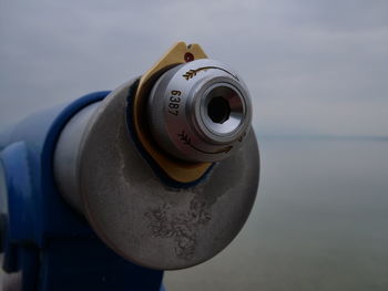 Close-up of coin-operated binoculars against sea