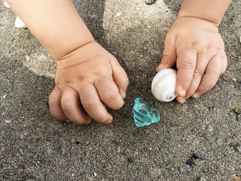 Cropped image of baby holding artificial snail toy on field