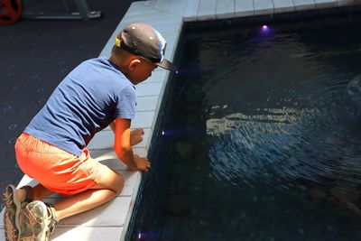 Side view of boy kneeling on poolside