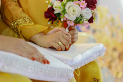 Midsection of bride and groom holding hands during wedding