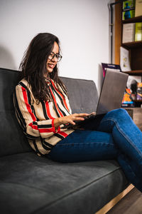 Smiling young woman using laptop while sitting at office