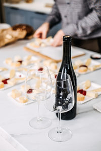 Preparing appetizers with wine for a gathering. unfocused hands arranging cheese and bread 