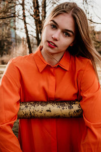 Portrait of beautiful young woman standing against trees