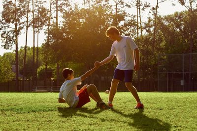 Full length of friends playing soccer on field