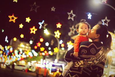 Mother and son on illuminated street at night