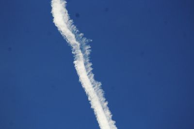 Low angle view of vapor trails against blue sky