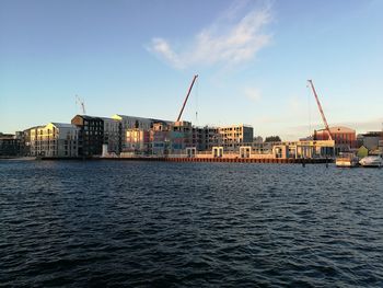 Sea by buildings in city against sky