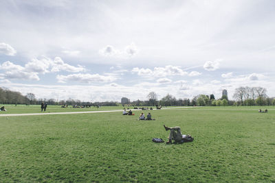 People on grassy field against sky