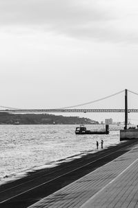 Suspension bridge over sea against sky