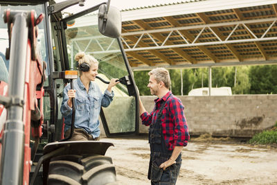 Couple communicating by tractor at farm