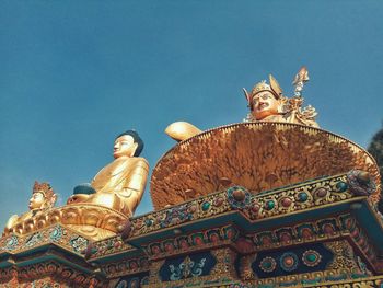 Low angle view of statue against temple against clear sky