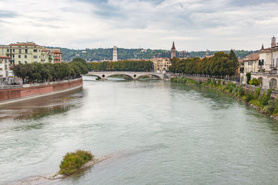 Arch bridge over river against buildings in city