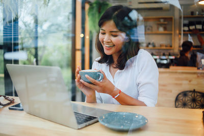 Smiling businesswoman enjoying coffee at cafe