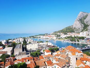 Aerial view of townscape by sea against clear blue sky