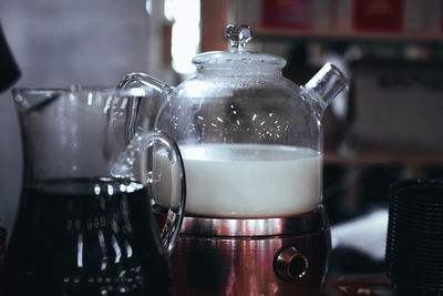 Glass teapot with white steamed milk for making indian masala tea. hot drink.