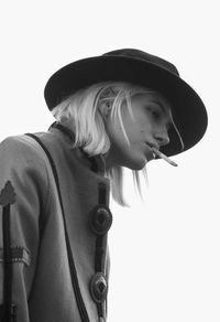 Low angle view of young woman smoking cigarette against clear sky