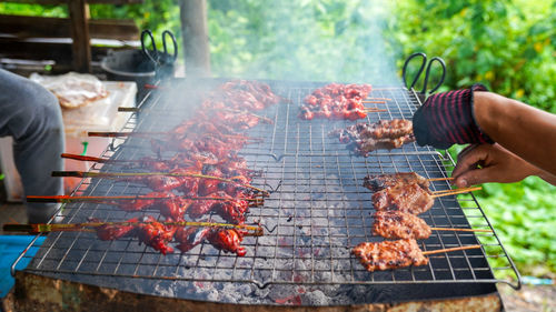 Midsection of man preparing food on barbecue grill