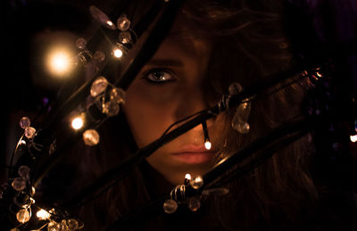 Close-up portrait of young woman with illuminated lighting equipment