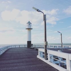 Lighthouse by sea against sky