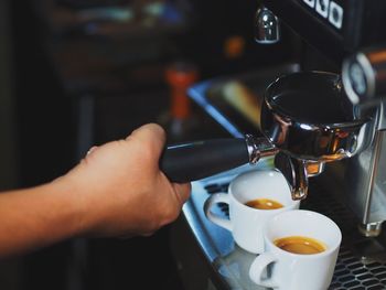 Close-up of hand pouring coffee in cafe