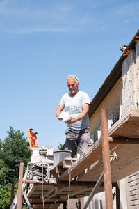 Masonry worker the bricklayer makes the facade of the house from gray bricks