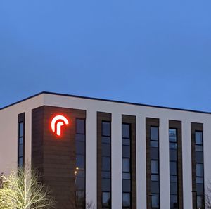 Low angle view of illuminated sign against clear blue sky