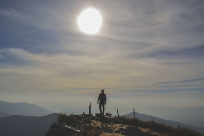 Man standing on mountain against sky during sunset