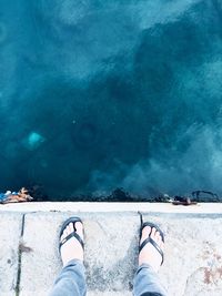 Low section of man standing by sea